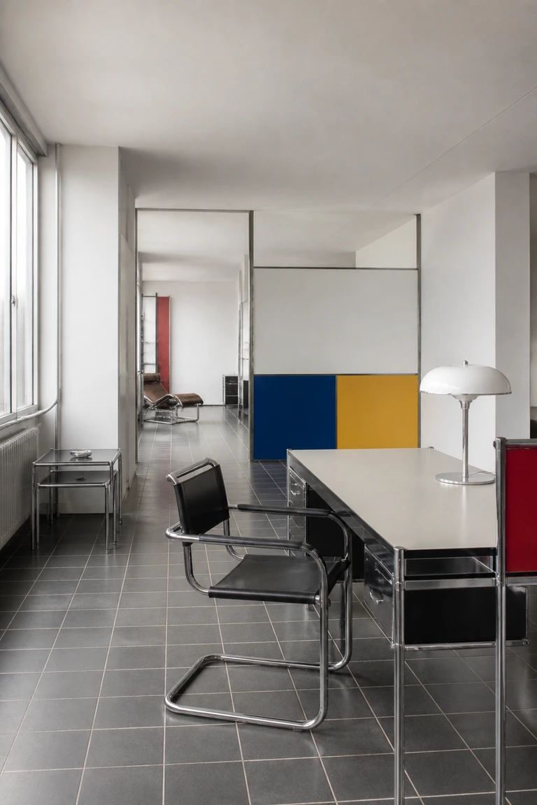 Bauhaus studio apartment with tubular steel chairs, modular furniture, a rational grid, and restrained primary-colour planes.
